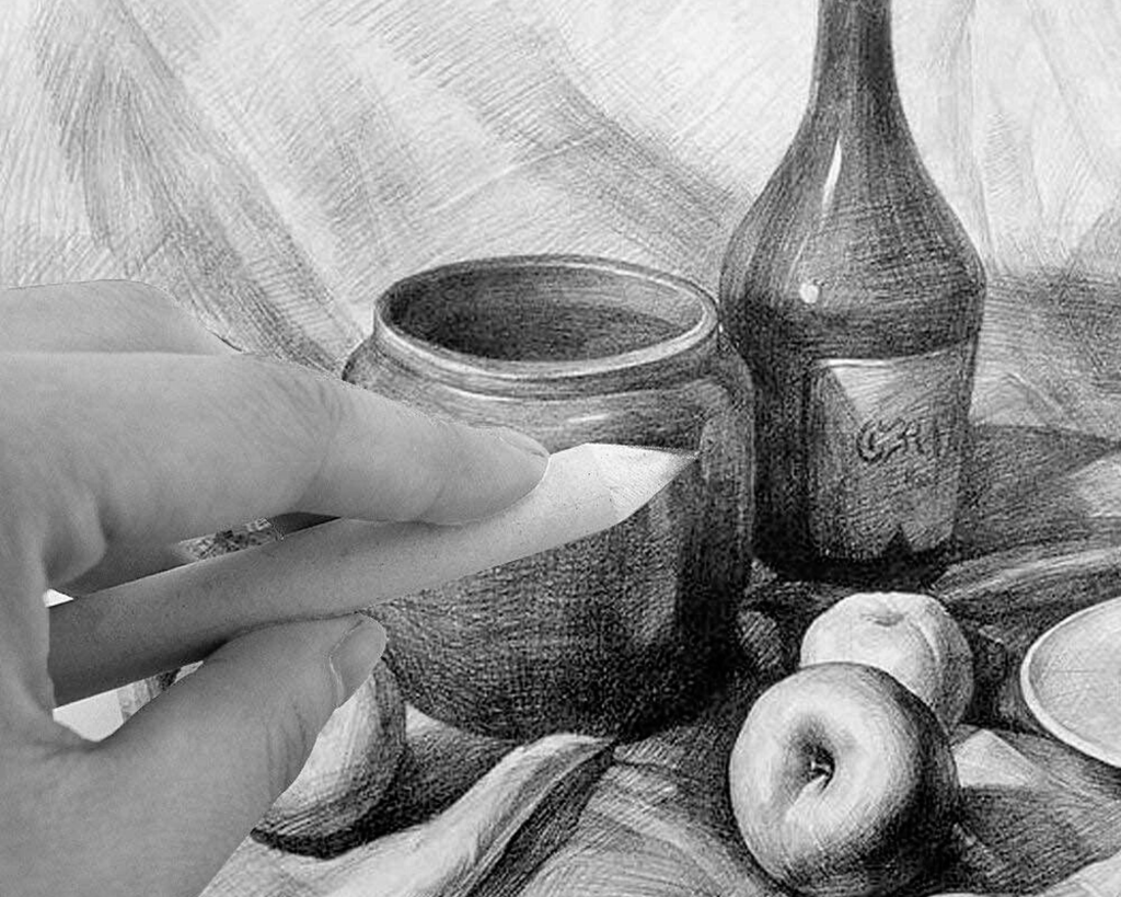 Une main d'homme qui tient une estompe sur un dessin de nature morte faite au crayon, un pot, une pomme, une bouteille