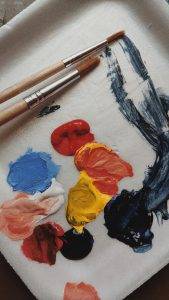 Une palette de peinture acrylique avec différentes couleurs et deux pinceaux